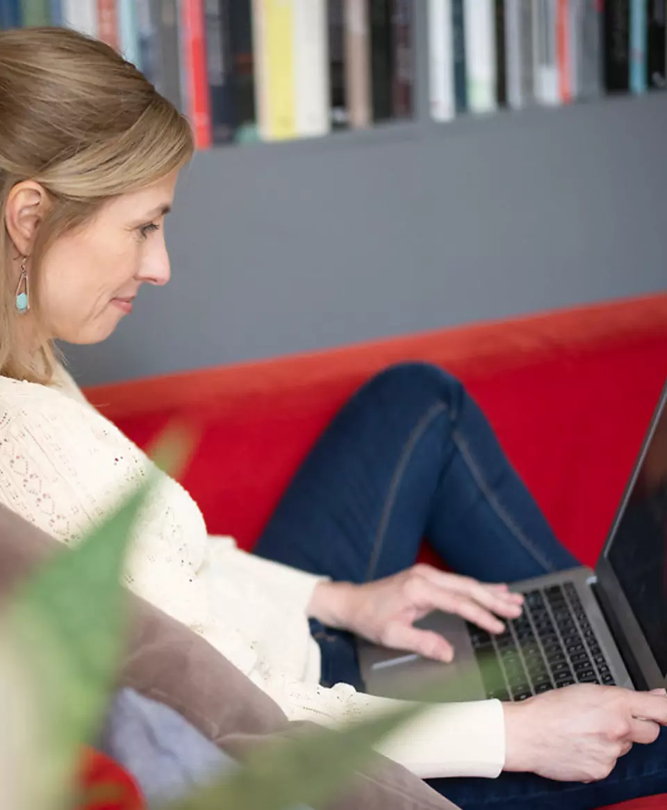 Persoana lucrand pe laptop in mod relaxat